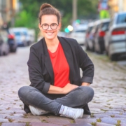 Katja Diehl sitzt auf der Straße zwischen Autos | Eltern-Gedöns-Podcast