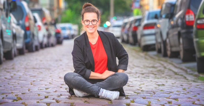 Katja Diehl sitzt auf der Straße zwischen Autos | Eltern-Gedöns-Podcast