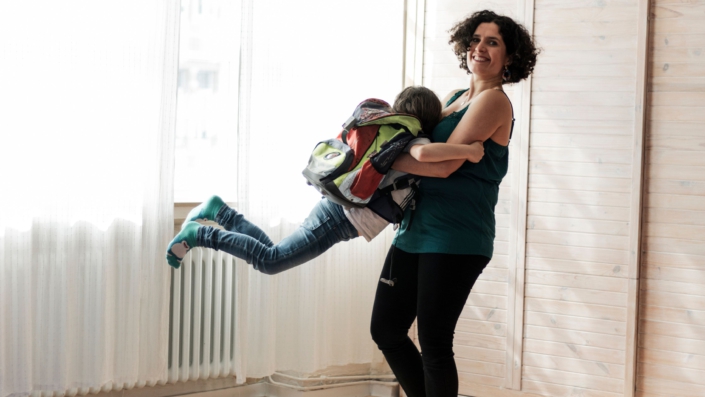 Kiran Deuretzbacher wirbelt ihr Kind umher, das einen Schulranzen trägt