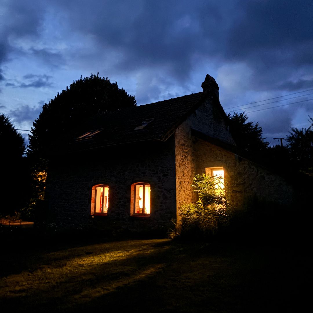 Warmens Licht fällt aus den Fenstern eines Hauses in der Abenddämmerung