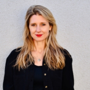 Porträtfoto von Laura Fröhlich. Die Autorin lehnt sich mit dem Rücken an eine Wand an