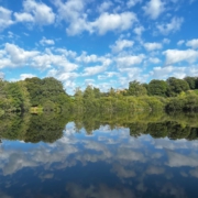 Foto: Himmel mit Wolken spiegelt sich in einem See.