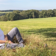 Sandra Knümann sitzt auf einem Feld, mit dem Rücken an einen Baum gelehnt