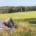 Sandra Knümann sitzt auf einem Feld, mit dem Rücken an einen Baum gelehnt