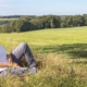Sandra Knümann sitzt auf einem Feld, mit dem Rücken an einen Baum gelehnt