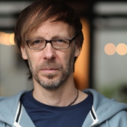 Foto von Christopher End, wie er freundlich, aber bestimmt den Betrachter direkt anschaut