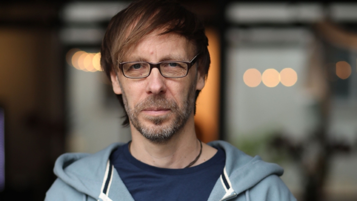 Foto von Christopher End, wie er freundlich, aber bestimmt den Betrachter direkt anschaut