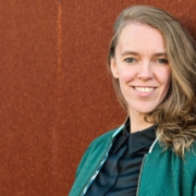 Foto von Stefanie Bohle, lehnt an einer Wand und lächelt in die Kamera