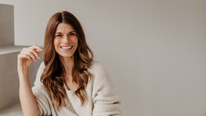 Foto von Lisa Reinheim (KLassenheld) lachend auf einer Treppe sitzend