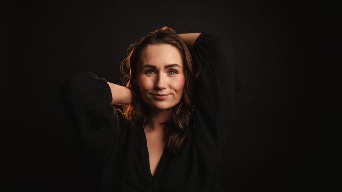 Porträtfoto von Maris Becker - nur Gesicht und Hände sind erkennbar, der Rest verschmilzt mit dem schwarze Hintergrund