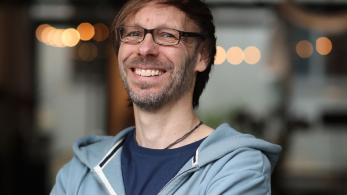 Porträtfoto von Christopher End, lachend, in die Kamera schauend