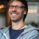 Porträtfoto von Christopher End, lachend, in die Kamera schauend