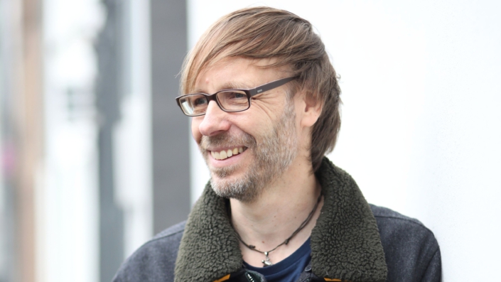 Porträt von Christopher End, Eltern-Coach, lehnt an Wand, lachend
